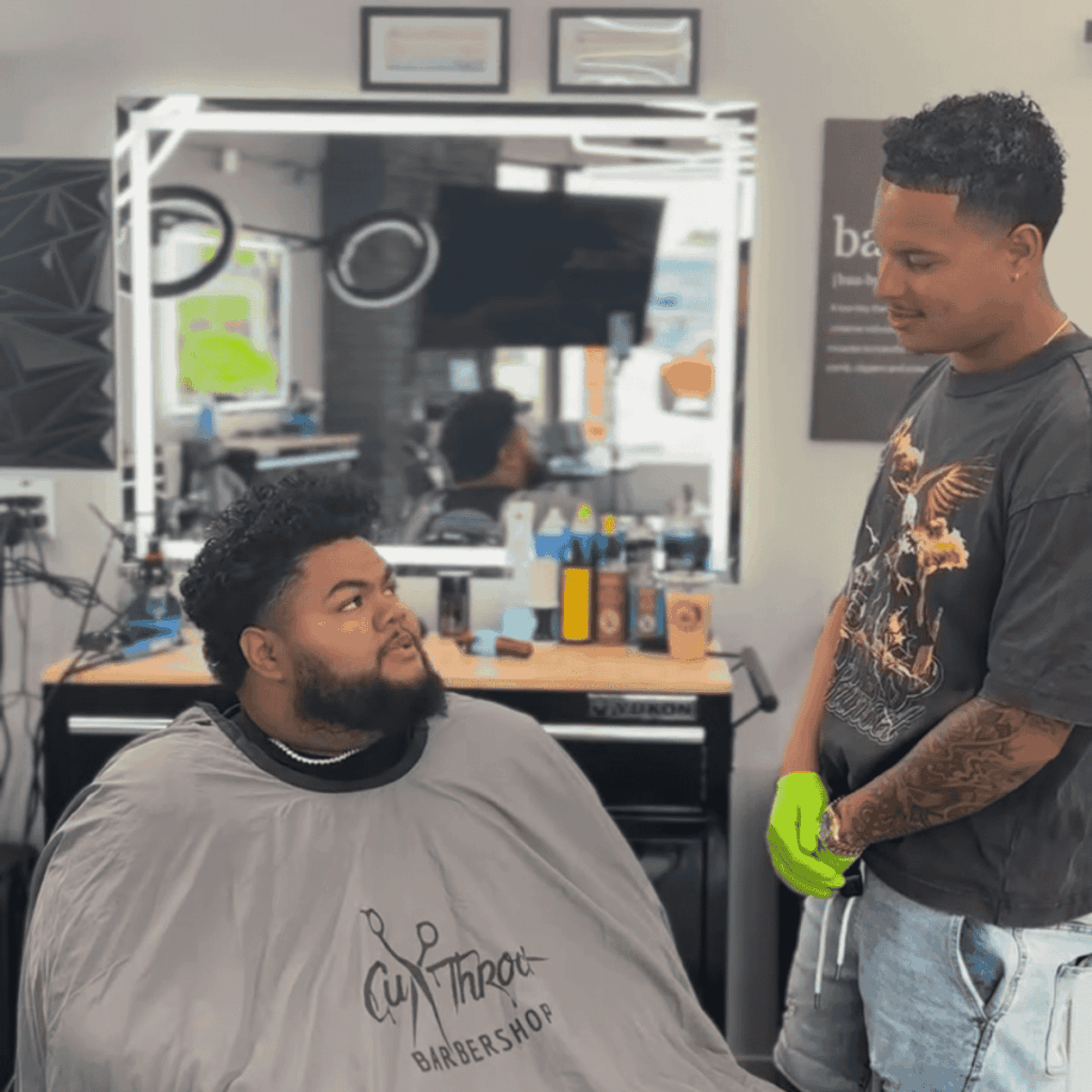 Friendly barber consulting with a client in a classic barber chair about their desired haircut style.
