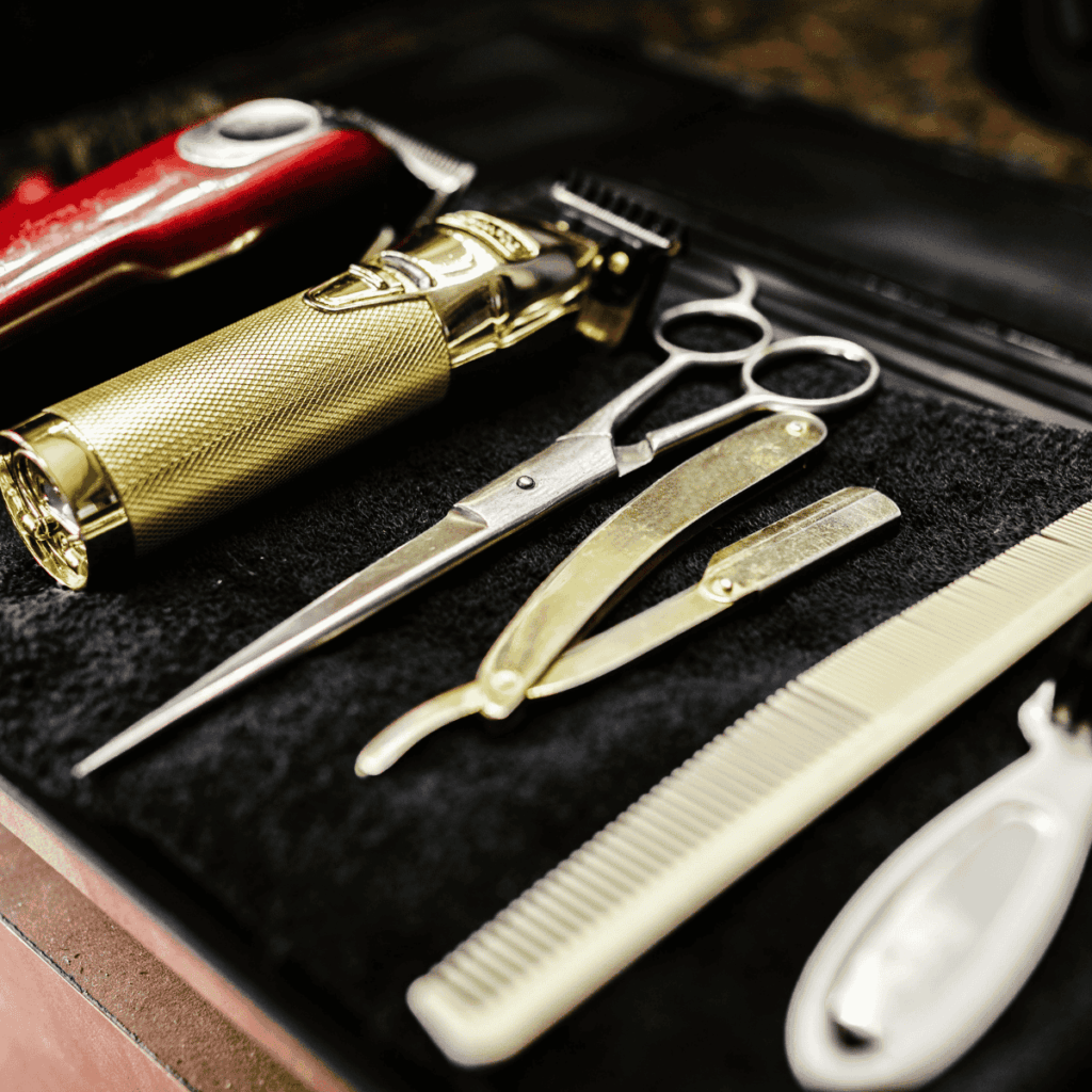 High-quality professional barber tools including gold clippers, shears, and combs laid out for a grooming session.