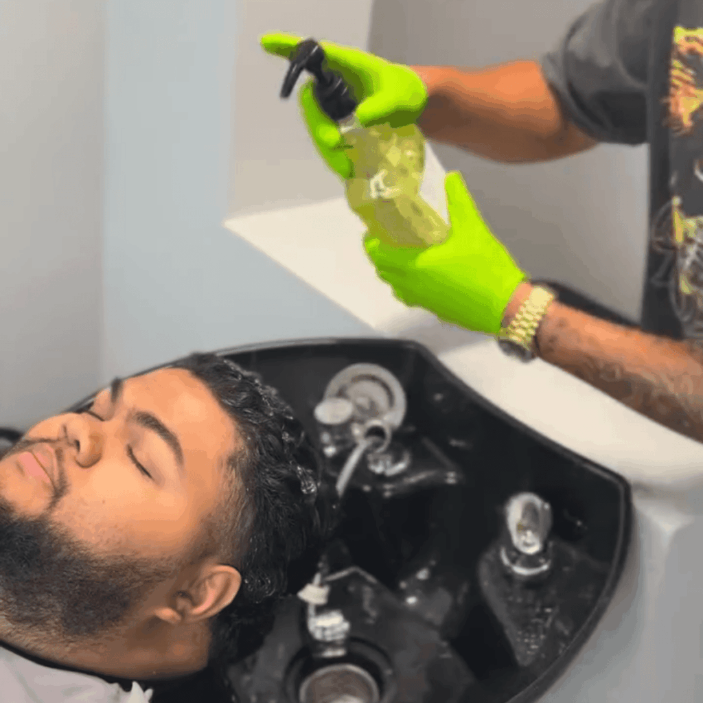 Barber providing a relaxing hair wash and scalp massage service at a professional wash station.