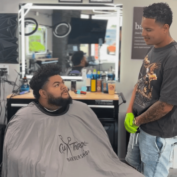 Friendly barber consulting with a client in a classic barber chair about their desired haircut style.