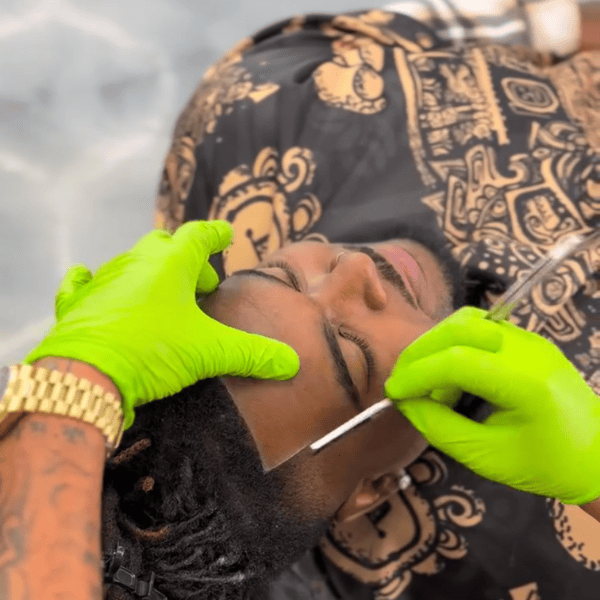 Master barber performing a crisp hairline line-up with a classic straight edge razor.