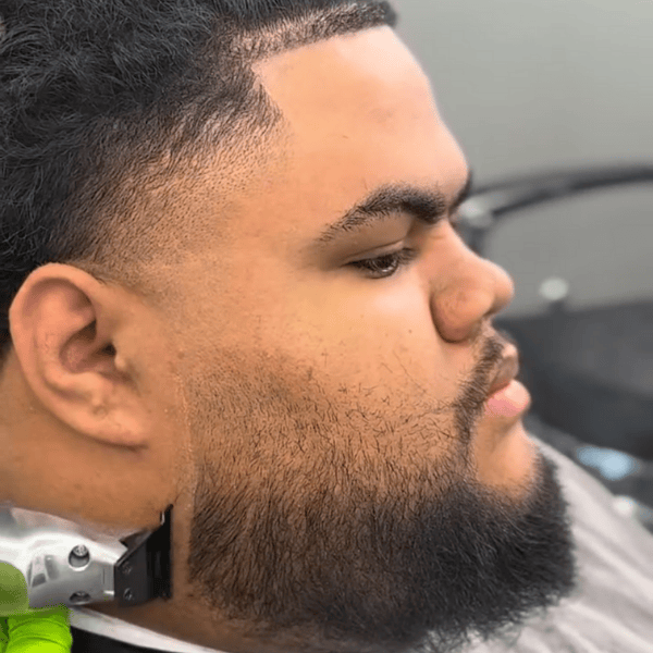 Barber performing final touch-ups on a haircut with silver professional trimmers.